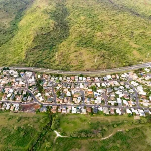 Aerial view of a residential area nestled in a lush green valley, showcasing homes surrounded by nature's beauty.